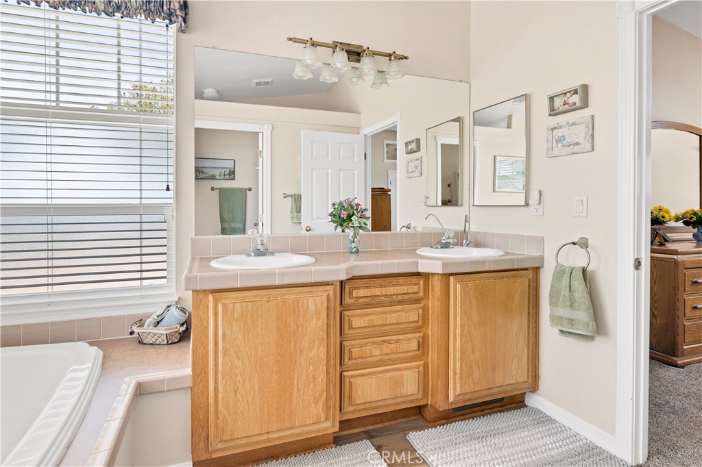 39597 Calle Escalona Temecula, CA 92592 - Photo 31 of 61 a bathroom with a sink a mirror and a bathtub