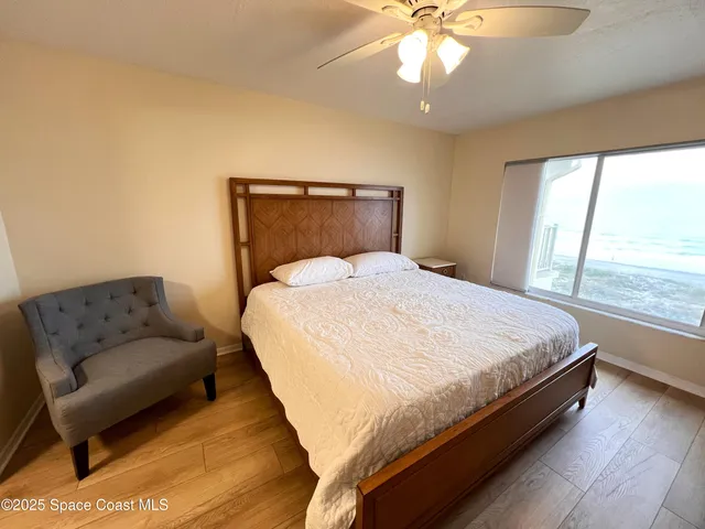 a bed sitting in a bedroom next to a window with a chandelier and couch