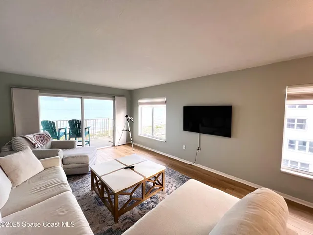 a living room with furniture a flat screen tv and a large window