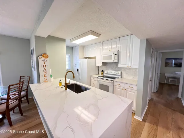 a kitchen with kitchen island a stove a sink a refrigerator dining table and chairs