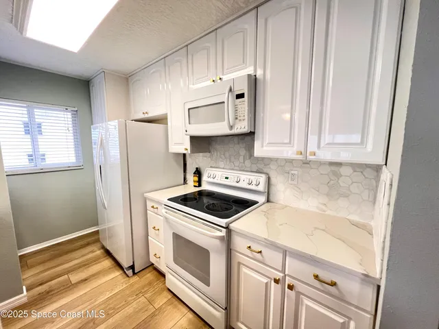 a kitchen with granite countertop a stove a sink and a refrigerator