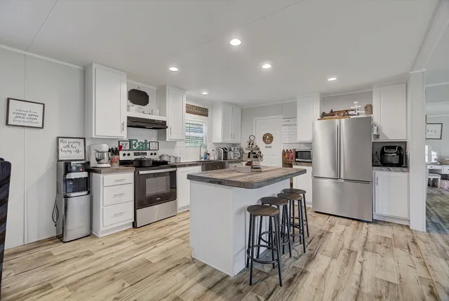 a kitchen with a refrigerator a sink dishwasher and a stove with wooden floor