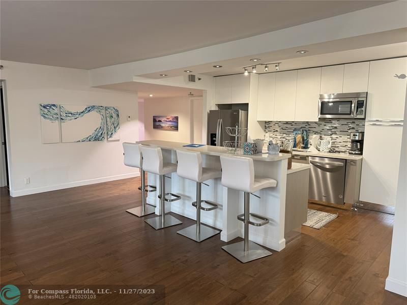 8877 Collins Avenue, Unit 307 Surfside, FL 33154 - Photo 2 of 15 a living room with stainless steel appliances furniture a rug and a kitchen view