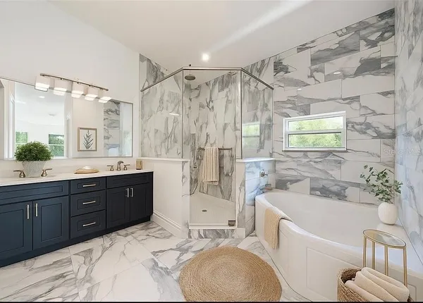 a bathroom with a granite countertop bathtub sink vanity mirror and shower