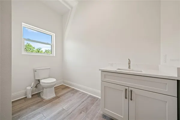 a bathroom with a toilet a sink and wooden floor