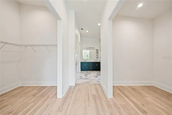 a view of a hallway with wooden floor and kitchen space