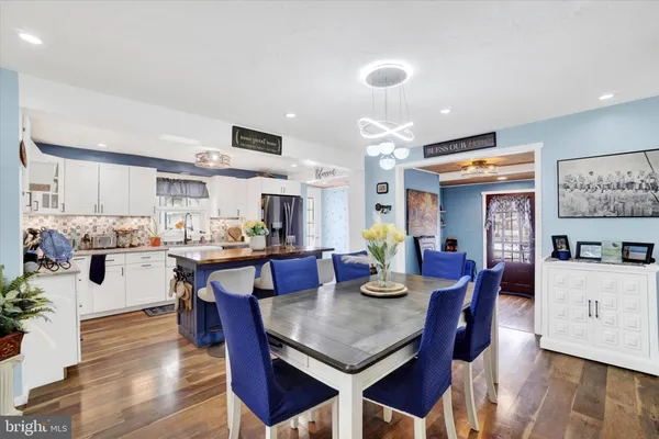 a kitchen with stainless steel appliances granite countertop a dining table chairs and white cabinets