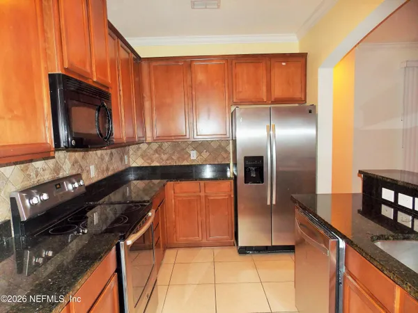 a kitchen with granite countertop a refrigerator stove and microwave