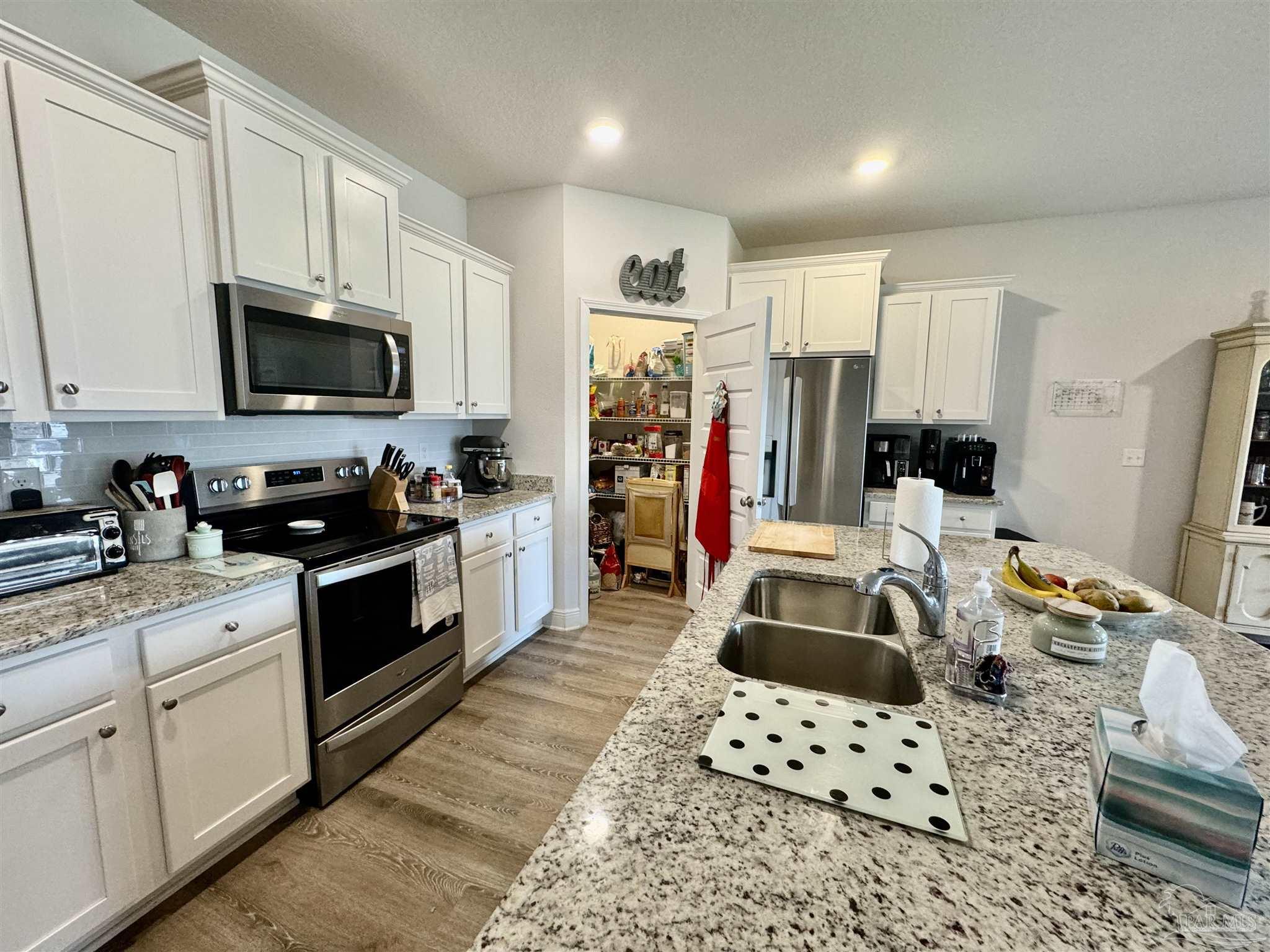 7787 Burnside Loop Pensacola, FL 32526 - Photo 11 of 32 a kitchen with stainless steel appliances a stove a sink a microwave a refrigerator and cabinets