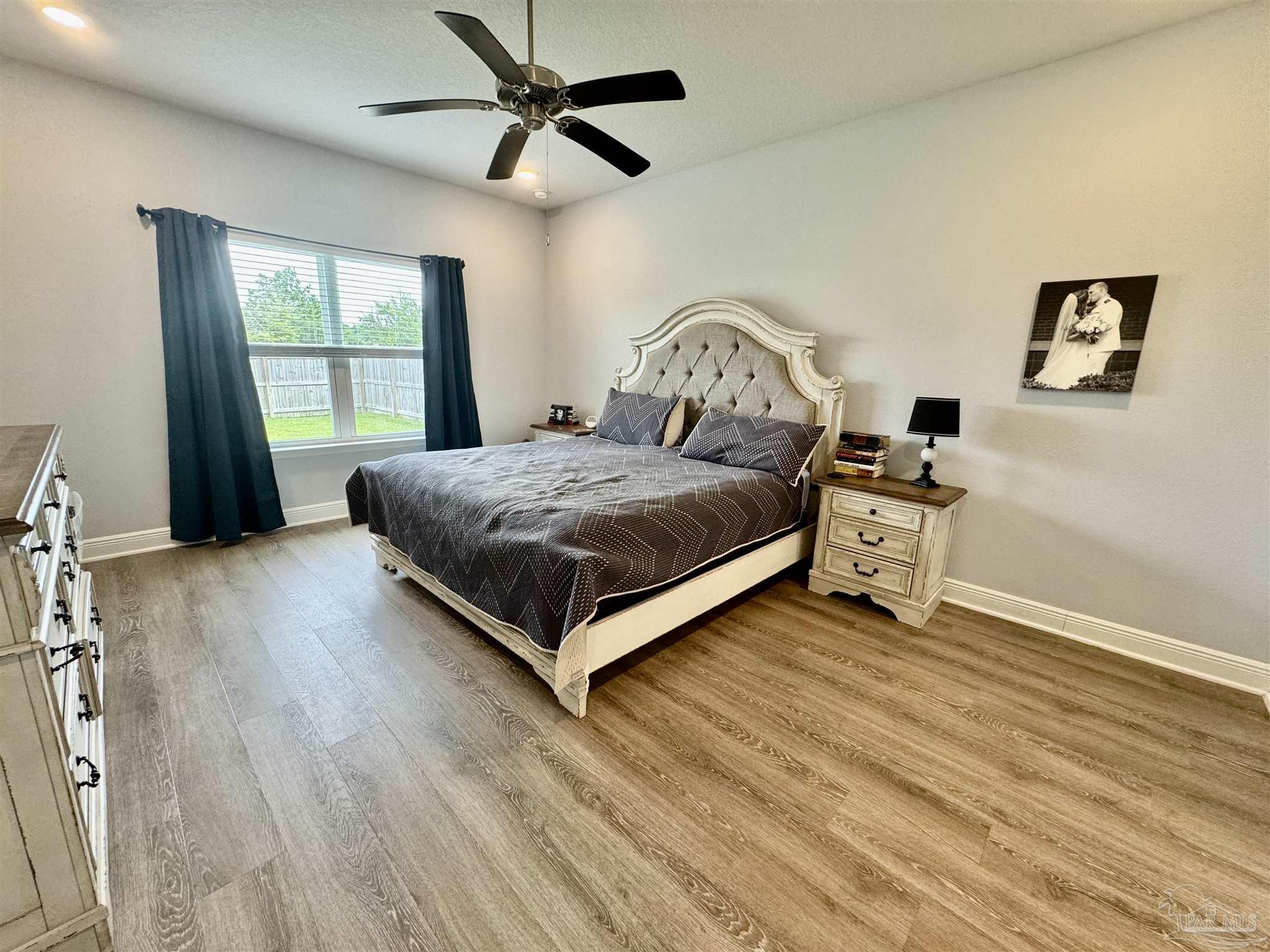 7787 Burnside Loop Pensacola, FL 32526 - Photo 19 of 32 a spacious bedroom with a bed a chandelier and a window