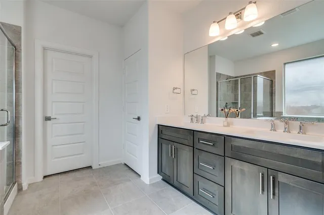 a spacious bathroom with a double vanity sink a large mirror and a shower
