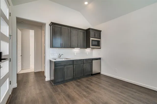 a kitchen with stainless steel appliances granite countertop a stove a sink and a refrigerator with wooden floors