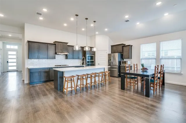 a kitchen with kitchen island granite countertop stainless steel appliances cabinets and wooden floor