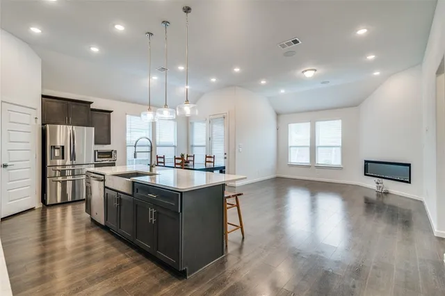 a kitchen with stainless steel appliances granite countertop a sink a stove and a wooden floors