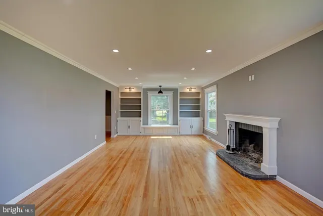 a view of an empty room with wooden floor fireplace and a window
