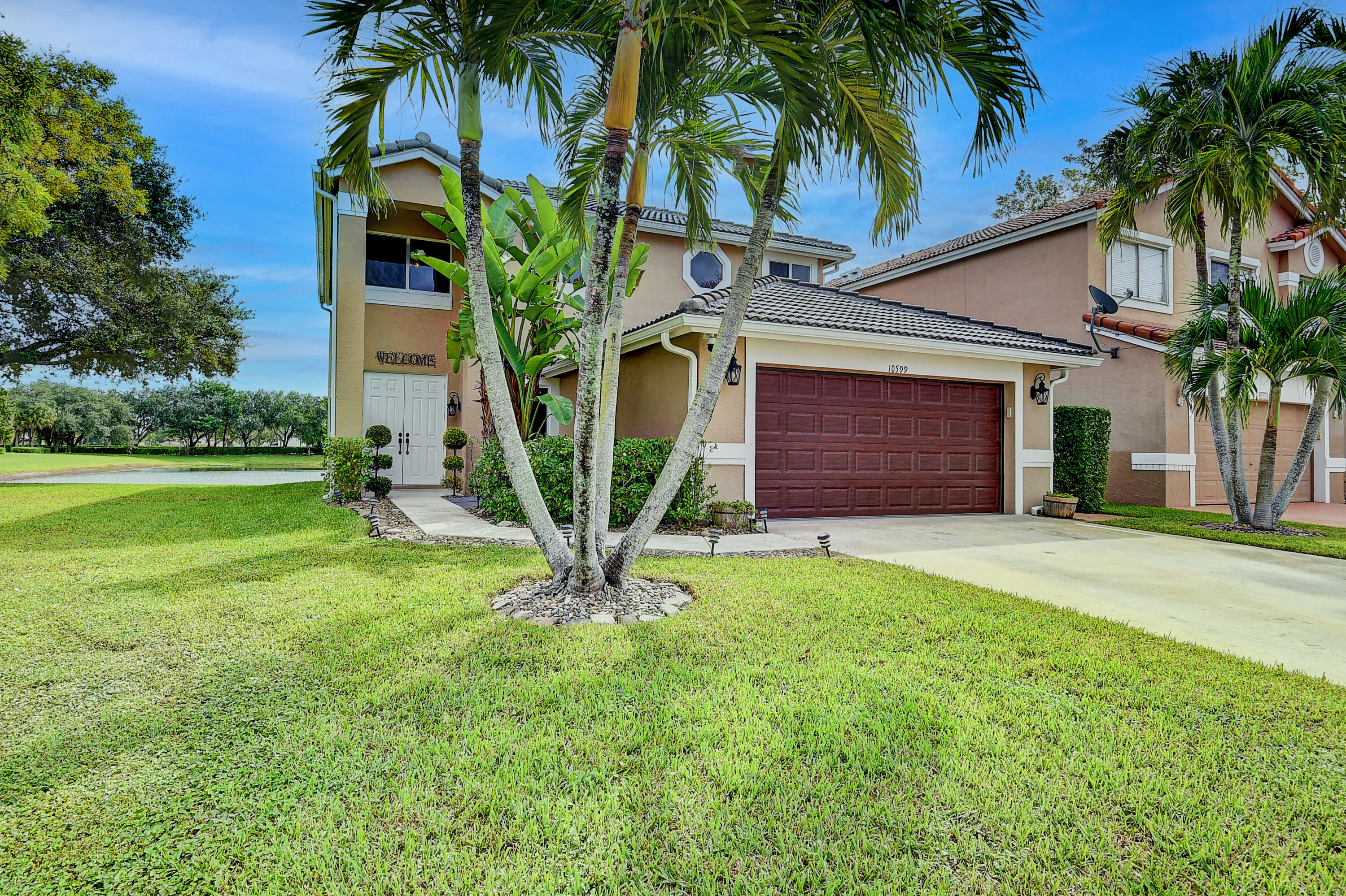 10599 Palm Spring Drive Boca Raton, FL 33428 - Photo 1 of 46 a front view of yellow house with a garden