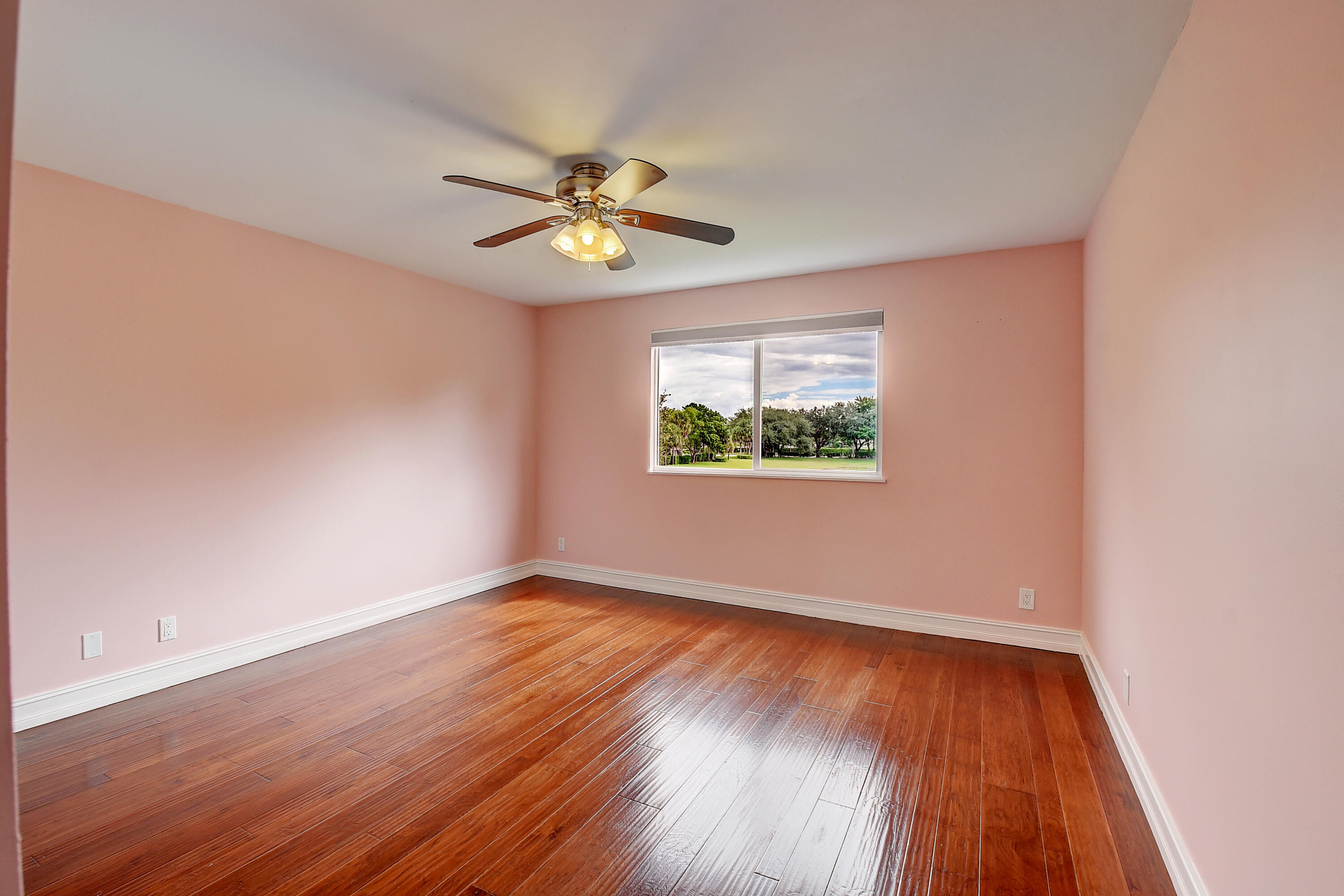 10599 Palm Spring Drive Boca Raton, FL 33428 - Photo 29 of 46 an empty room with wooden floor chandelier fan and windows