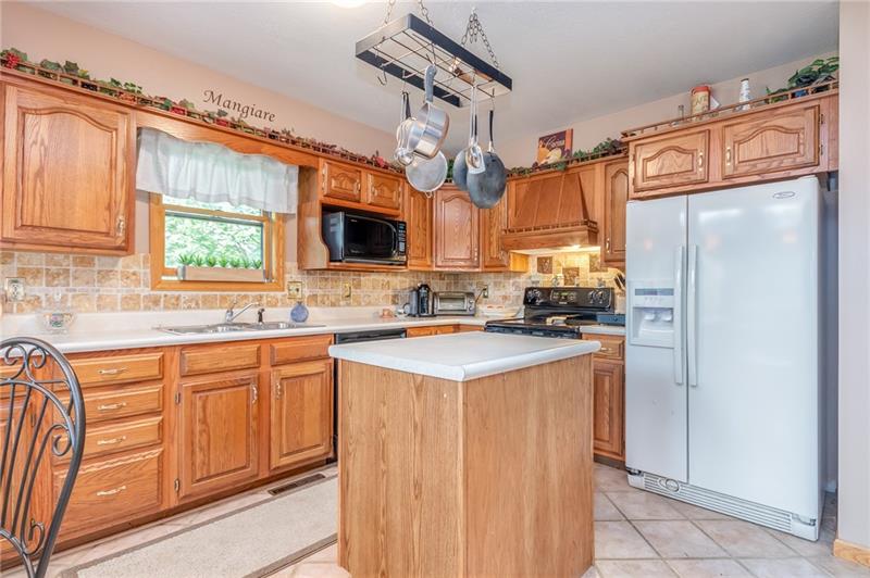 1473 Lovi Road Freedom, PA 15042 - Photo 6 of 22 A kitchen island, pendant lighting, tile floors & stone tile backsplash contribute to the refined, yet rugged atmosphere of the home.