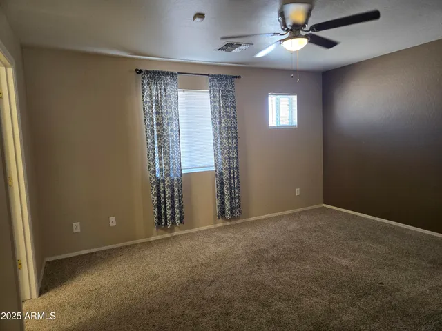 an empty room with windows and fan