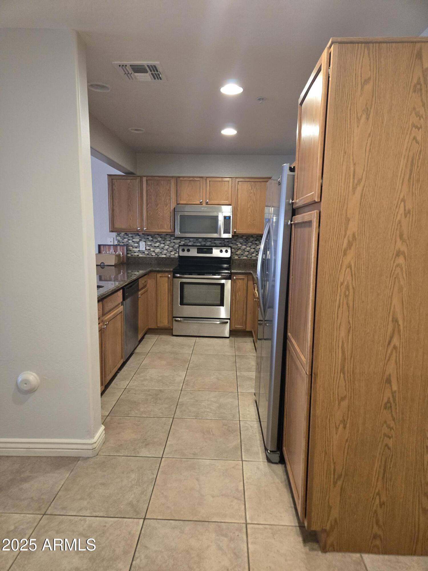 16021 North 30th Street, Unit 119 Phoenix, AZ 85032 - Photo 4 of 28 a kitchen with stainless steel appliances granite countertop a refrigerator and a stove top oven
