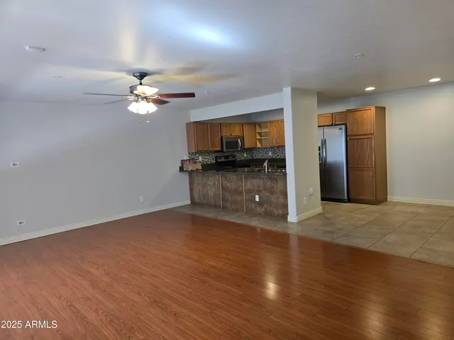an empty room with wooden floor and stainless steel appliances