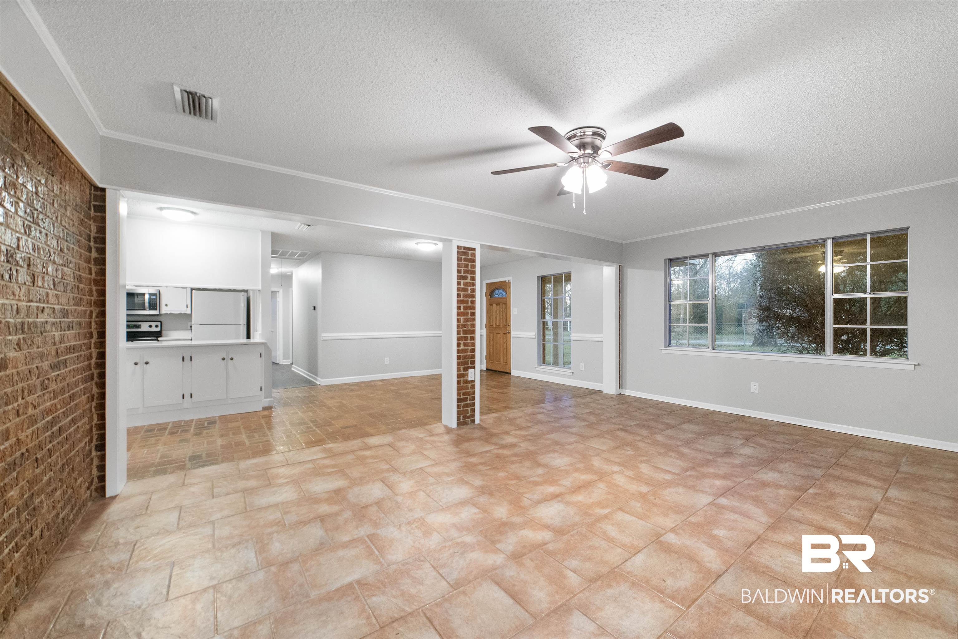 11833 Old Moffat Road Wilmer, AL 36587 - Photo 3 of 23 Unfurnished living room featuring ceiling fan, brick wall, a textured ceiling, and visible vents