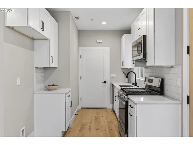 a kitchen with stainless steel appliances granite countertop white cabinets a stove top oven a sink and dishwasher