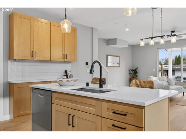 a living room with stainless steel appliances kitchen island a sink dishwasher a stove and a dining table with wooden floor