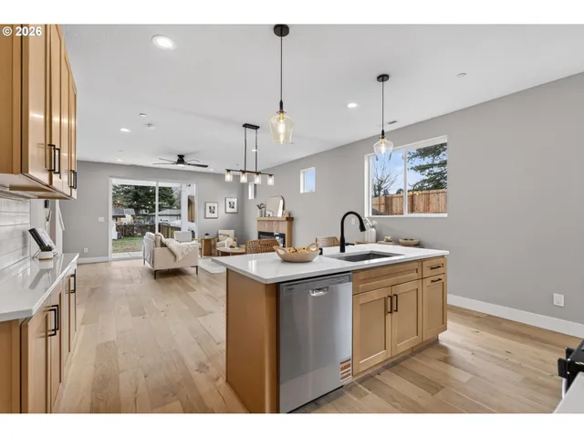 a kitchen with stainless steel appliances kitchen island granite countertop a sink cabinets and wooden floor