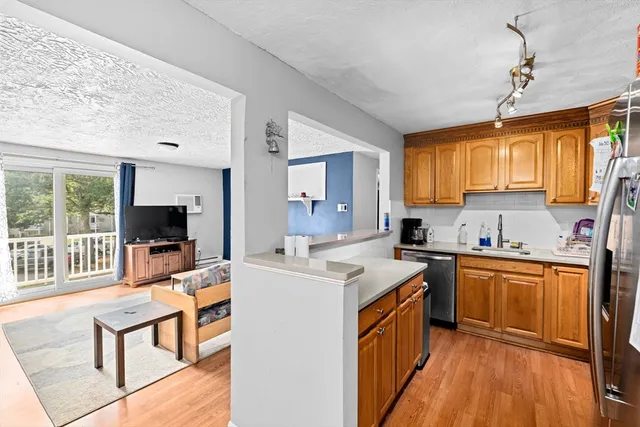 a kitchen with stainless steel appliances granite countertop a stove top oven a sink dishwasher a dining table and chairs with wooden floor