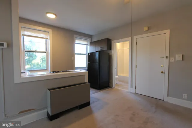 an empty room with a window and refrigerator