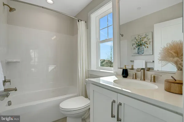 a bathroom with a granite countertop sink a toilet a mirror a vanity a bathtub and shower