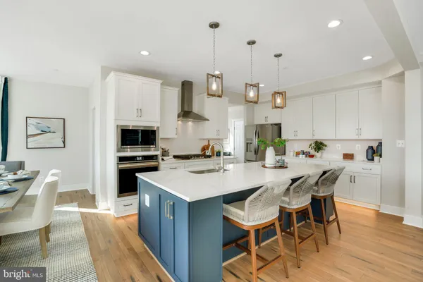 a kitchen with stainless steel appliances kitchen island granite countertop a sink a stove a dining table and chairs