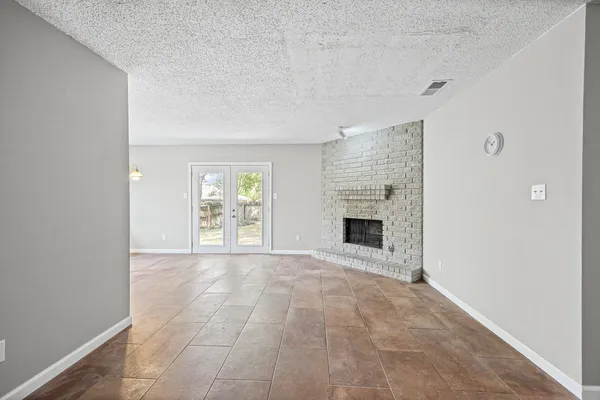 a view of an empty room with a fireplace and a window