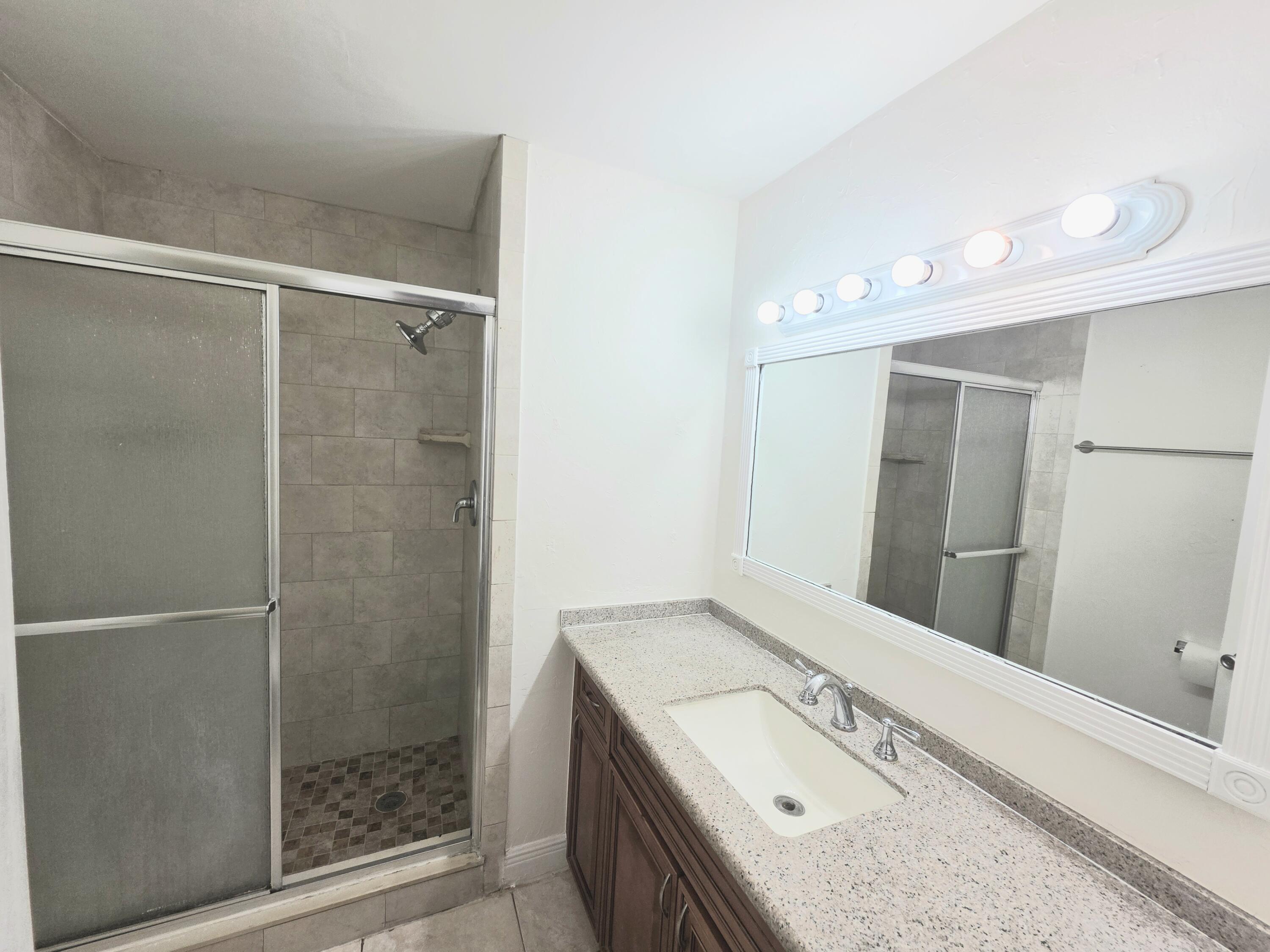 683 Northwest 13th Street, Unit 27 Boca Raton, FL 33486 - Photo 9 of 16 a bathroom with a granite countertop sink a mirror and shower