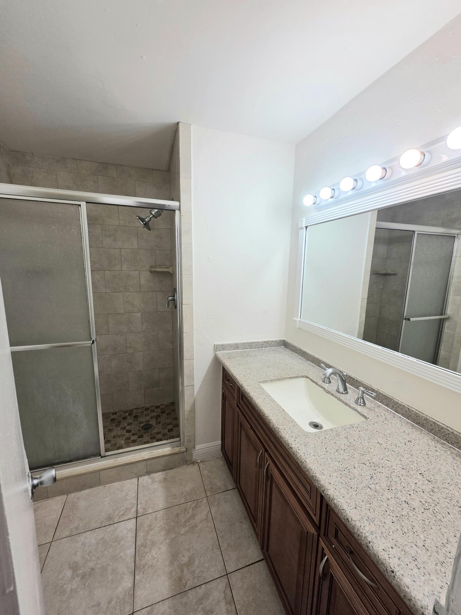 683 Northwest 13th Street, Unit 27 Boca Raton, FL 33486 - Photo 10 of 16 a bathroom with a granite countertop sink a toilet a mirror and shower