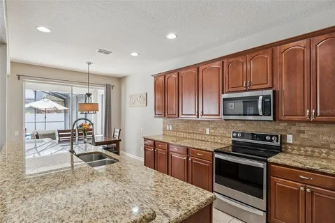 a kitchen with granite countertop a stove a sink and a microwave