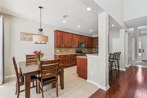 a kitchen with a dining table chairs wooden floor cabinets appliances and a center island