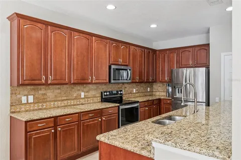 a kitchen with stainless steel appliances granite countertop a stove top oven a sink dishwasher and wooden cabinets with wooden floor