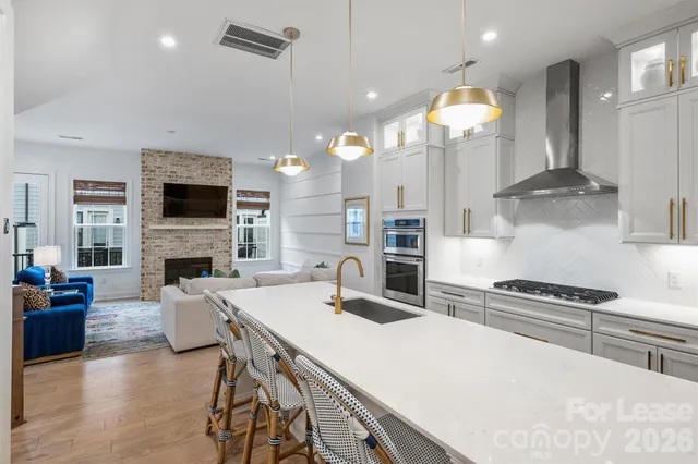 a kitchen with stainless steel appliances kitchen island granite countertop a dining table chairs sink refrigerator and microwave