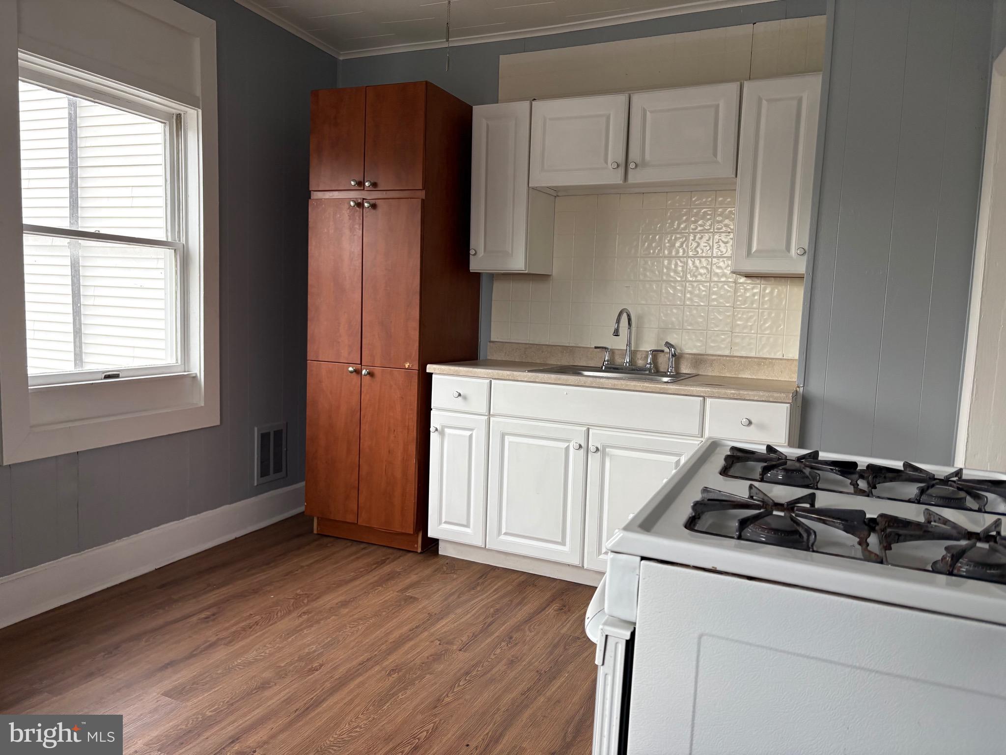 a kitchen with a stove a sink and wooden floor