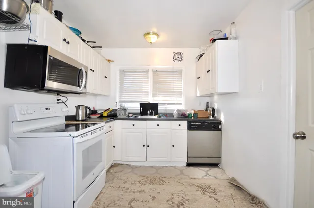 a kitchen with stainless steel appliances white cabinets a sink a stove a refrigerator and microwave