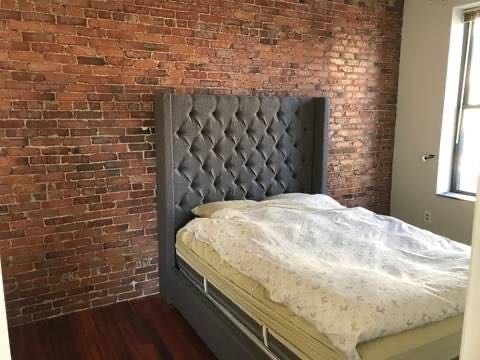 78 Berkeley Street, Unit 6 Boston, MA 02116 - Photo 2 of 6 a bed sitting in a bedroom next to a brick wall