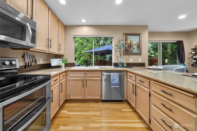 a kitchen with stainless steel appliances granite countertop a stove a sink and a microwave