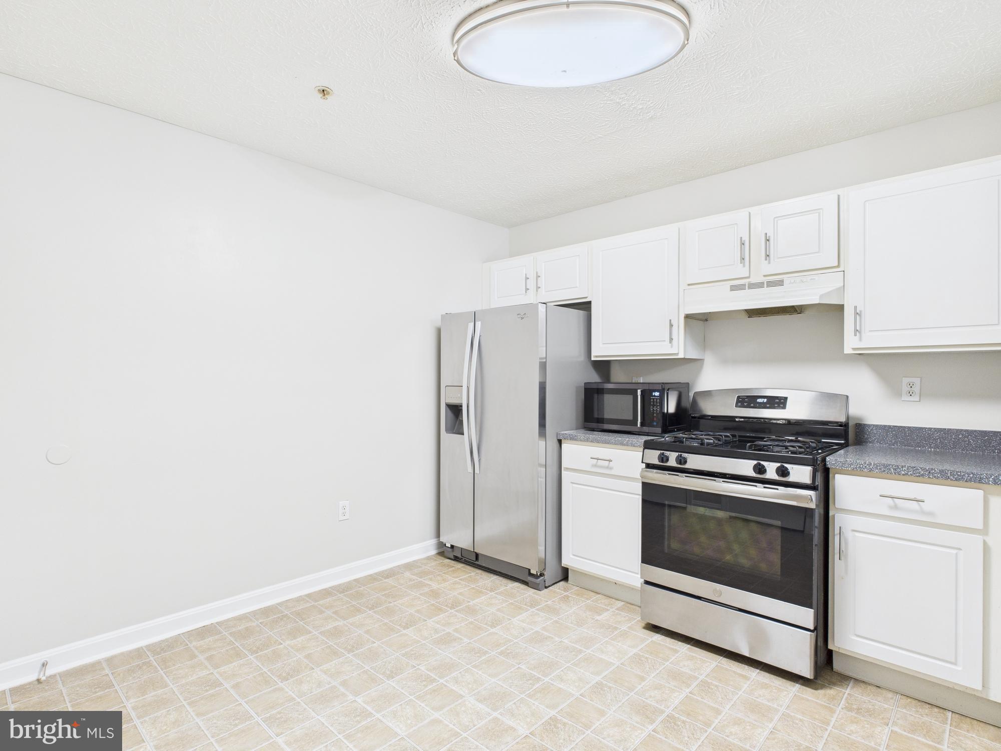 8067 Brookstone Court, Unit 100 Severn, MD 21144 - Photo 6 of 36 a kitchen with stainless steel appliances granite countertop a stove a refrigerator and a sink