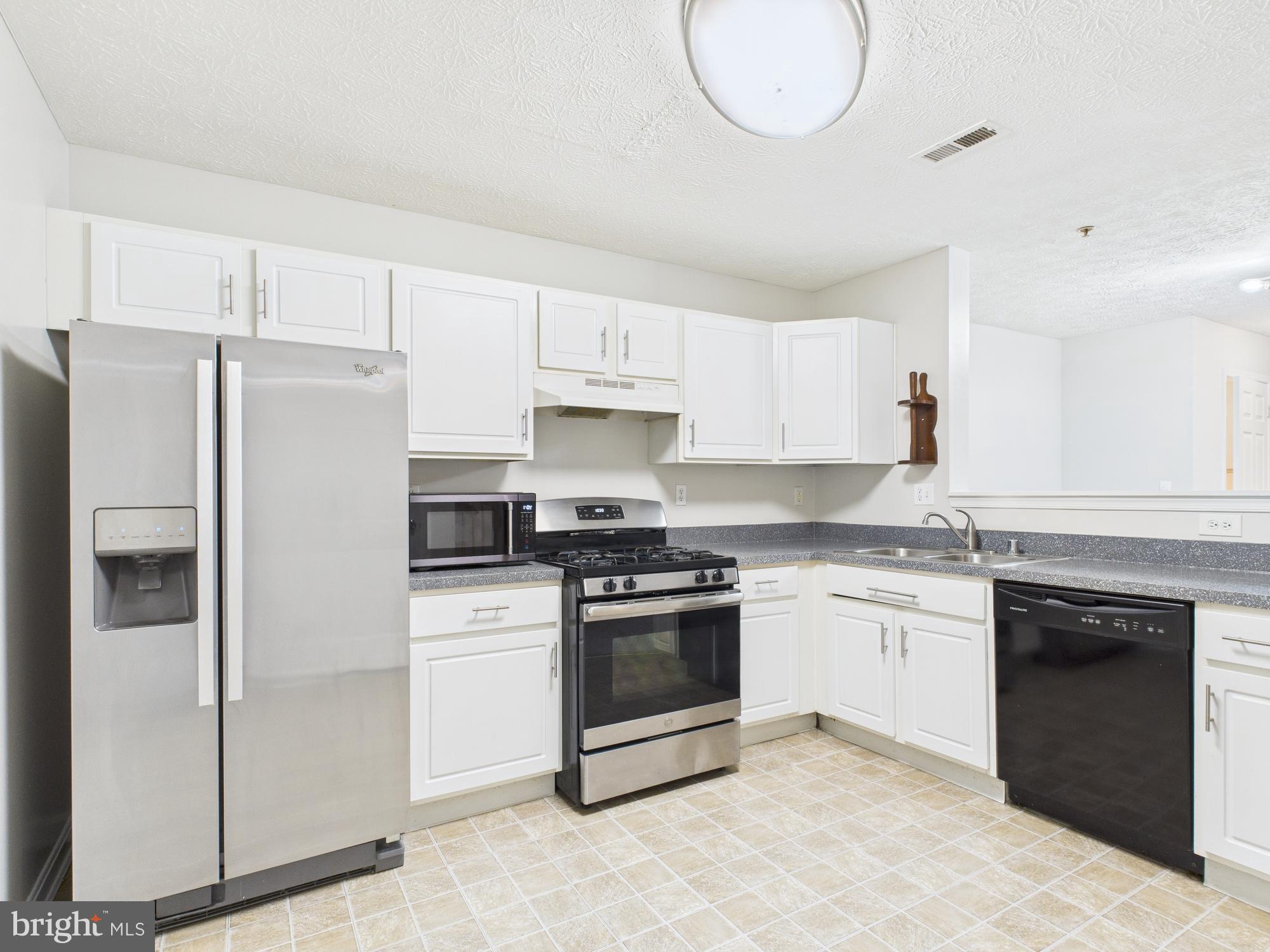 8067 Brookstone Court, Unit 100 Severn, MD 21144 - Photo 7 of 36 a kitchen with stainless steel appliances granite countertop a stove a refrigerator and a sink