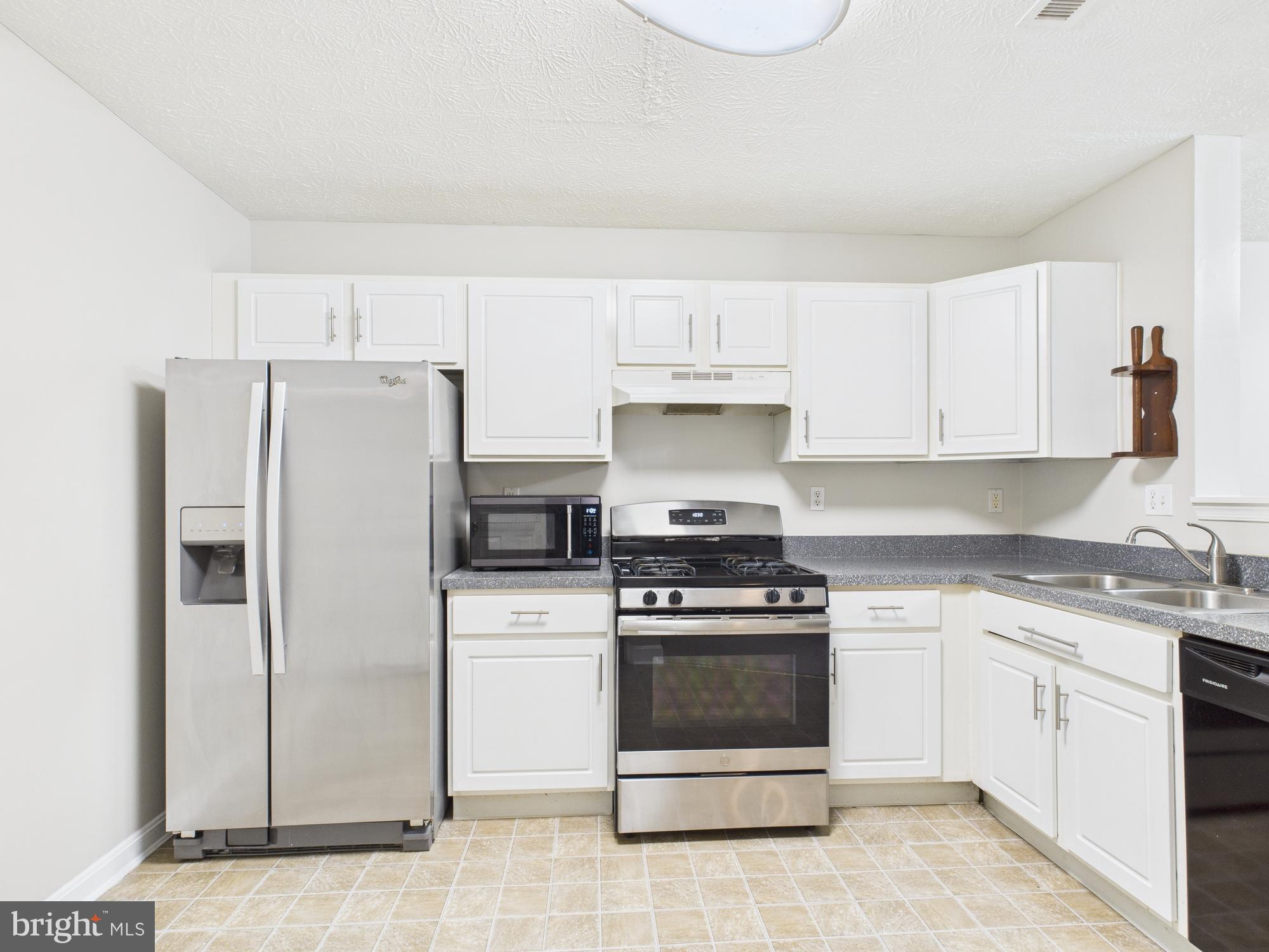 8067 Brookstone Court, Unit 100 Severn, MD 21144 - Photo 8 of 36 a kitchen with white cabinets and white appliances