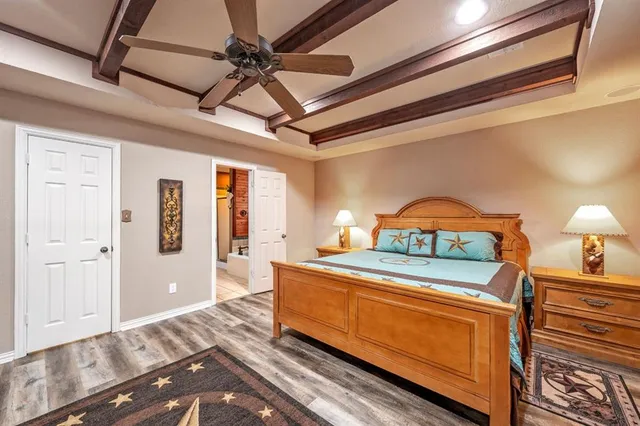 a bedroom with a bed a dresser and wooden floor