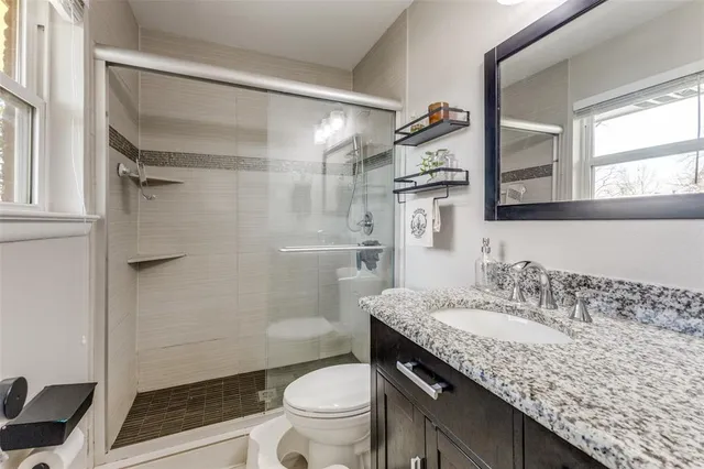 a bathroom with a granite countertop sink toilet and shower