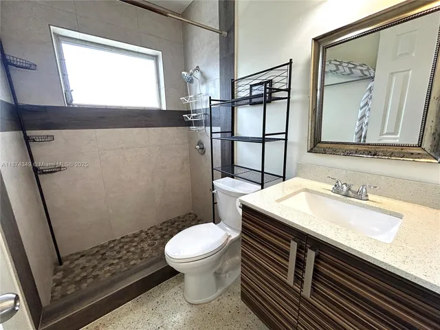 a bathroom with a sink a toilet a mirror and shower